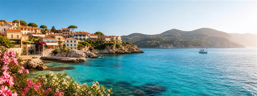A sunlit Mediterranean bay and coastal village